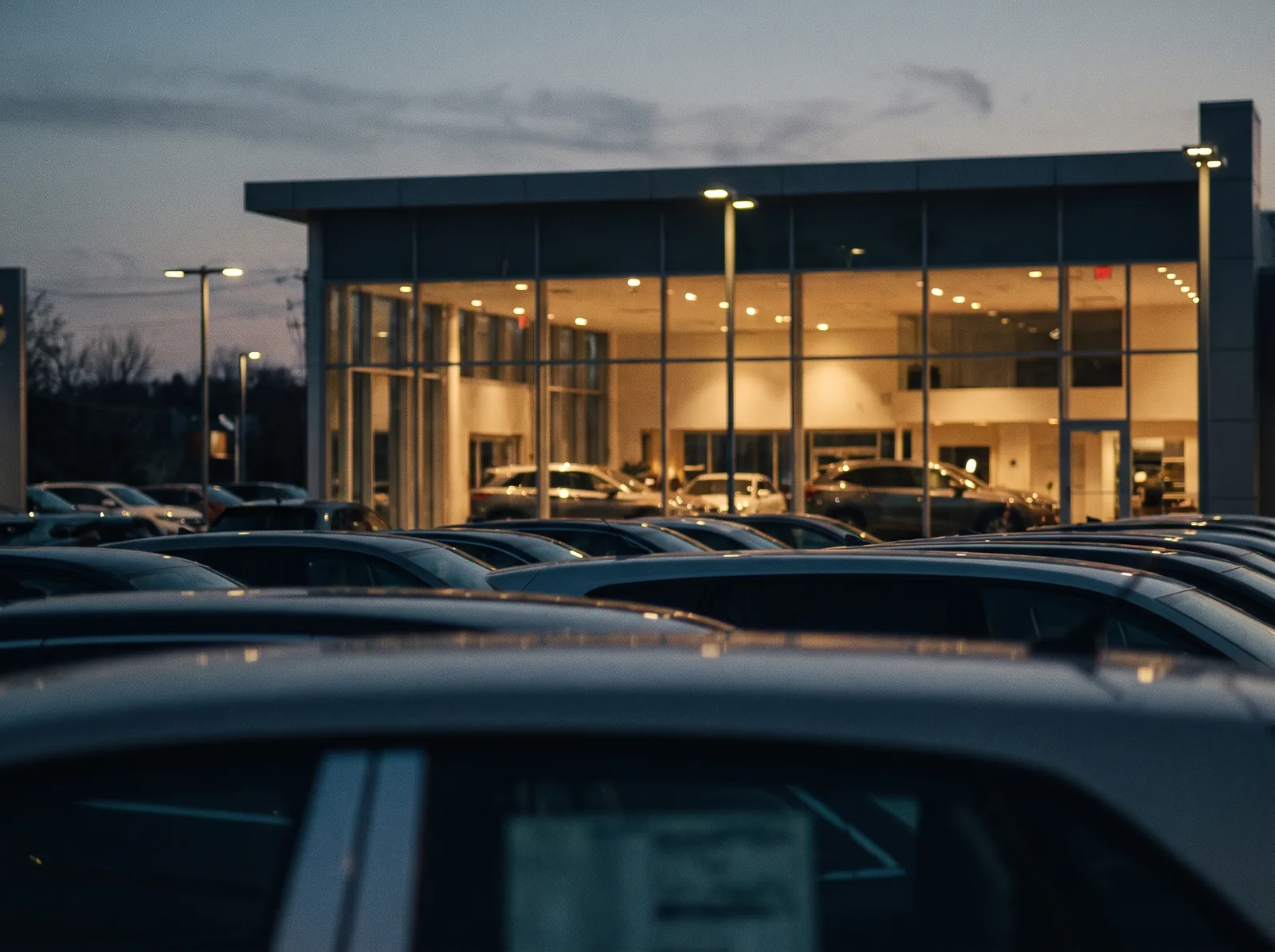 Autohaus-Vorplatz in der Dämmerung mit beleuchtetem Ausstellungsraum